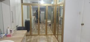Ein Badezimmer mit Glasschiebetüren, im Hintergrund eine Person. in der Unterkunft Casa Ivana in Guayaquil