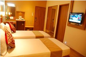 a hotel room with two beds and a television at Hotel Rajtara in Satara