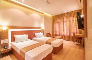 a hotel room with two beds and a television at Hotel Rajtara in Satara