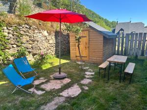 a table and two chairs and an umbrella in a yard at La Maison du Patou in Cadéac +13 photos
