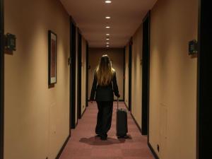 a woman walking down a hallway with a suitcase at Mercure Prishtina City in Prishtinë