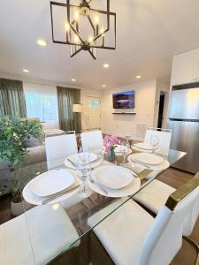 a dining room with a glass table and white chairs at Two Trees Retreat in Salt Lake City