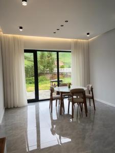 a dining room with a table and chairs and a large window at Shahdag Mountain Breeze in Qusar