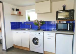 a kitchen with a washing machine and a microwave at Chrisme in Saint-Hilaire-Fontaine