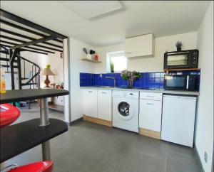 a kitchen with a washing machine and a microwave at Chrisme in Saint-Hilaire-Fontaine