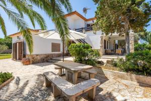a picnic table and benches in front of a house at Can Jordi in Cala Llombards
