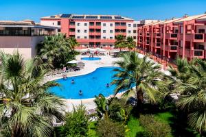 an aerial view of a resort swimming pool with palm trees at Leo Punta Umbría in Punta Umbría