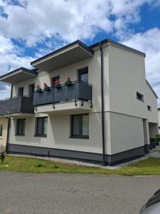 a white house with flowers on a balcony at Apartman JAMI in Spišské Podhradie