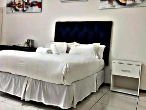 a bedroom with a large white bed with a blue headboard at Victoria City Lodge in Pretoria