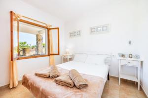 a white bedroom with a bed with pillows on it at Can Jordi in Cala Llombards