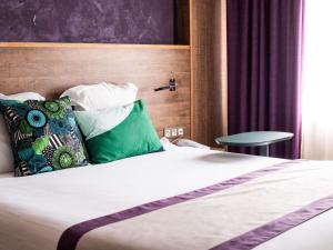 a hotel room with a bed with green pillows at Ibis Styles Cayenne Centre Amazonia in Cayenne