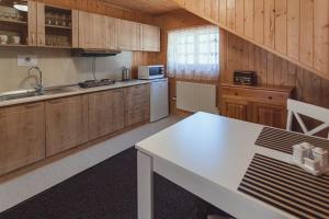 a kitchen with wooden cabinets and a white table at Chata Borovec in Veľké Borové +4 photos