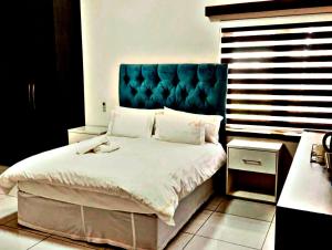 a bedroom with a large bed with a blue headboard at Victoria City Lodge in Pretoria +16 photos