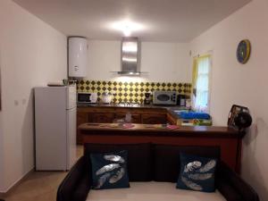 a kitchen with a couch and a white refrigerator at Le camphrier in Salazie +2 photos