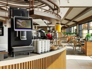 a coffee shop with a tv on the counter at Novotel Tbilisi Center in Tbilisi City