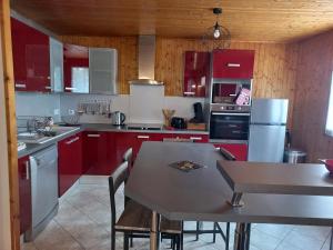 a kitchen with red cabinets and a table with chairs at Isa's Little Cottage in Saint-Bonnet-de-Chirac