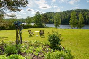 two chairs and a table in a field with a lake at Old School in Suolahti
