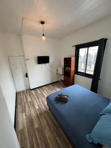 a bedroom with a blue bed and a flat screen tv at VOY Hostales - Oriente in Viña del Mar