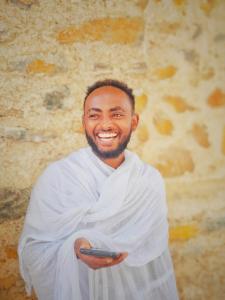a man is smiling while holding a cell phone at Abel haile in Moyalē