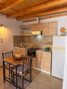 a kitchen with a table and a white refrigerator at Κουρείον Kourion in Agios Vlasios +4 photos