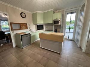 a large kitchen with green cabinets and a clock on the wall at La Maison du Bief in Écuisses