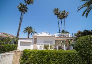 a white house with palm trees and bushes at Villa Marie in Benicarló