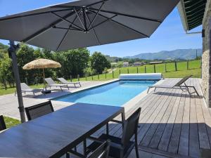 a patio with a table and an umbrella and a pool at Ibarnia in Suhescun