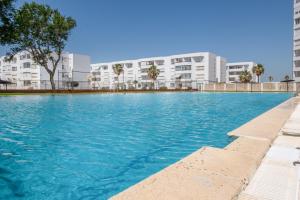 a large swimming pool with buildings in the background at Valdelagrana en Primera Linea in El Puerto de Santa María