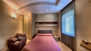 a bedroom with a bed and a chair and a window at Tornola Luxury Rooms in Termoli