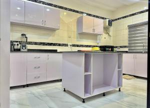 a kitchen with white cabinets and a purple island at Serene 5 Bedroom Duplex With Exclusive Compound in Iseri +25 photos