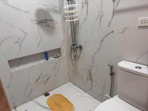 a white bathroom with a shower and a toilet at Urban Canopy City Forest Staycation in Tigbawan +7 photos