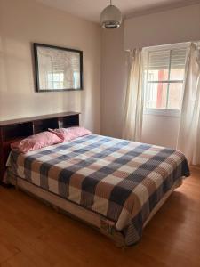 a bedroom with a bed with a plaid blanket on it at Osiris Apart in Comodoro Rivadavia