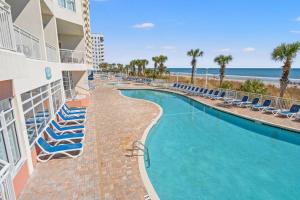 a resort swimming pool with lounge chairs and the beach at Bay Watch Resort 1735 - Direct Oceanfront Balcony with Pools and Lazy River in Myrtle Beach