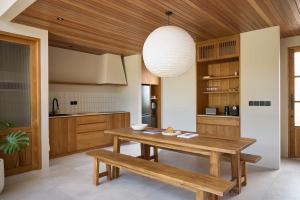 a kitchen with a wooden table and a wooden ceiling at The Young Villas Tropical Villas in Seseh in Canggu +17 photos