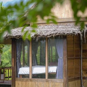 a wooden hut with a window with a thatched roof at Mai Chau Mountain Delight in Mai Châu