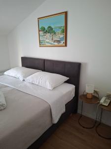 a bedroom with a bed with a picture on the wall at Hotel Adria in Kaštela
