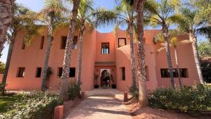a pink building with palm trees in front of it at Villa Amazonika By La Siredrah in Segraga