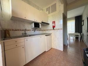 a kitchen with white cabinets and a sink and a table at Apartamentos Los Jazmines in Torremolinos