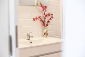 ein Waschbecken im Badezimmer mit einer Vase mit Blumen darin in der Unterkunft Casa do Armando in Achadinha + 36 Fotos