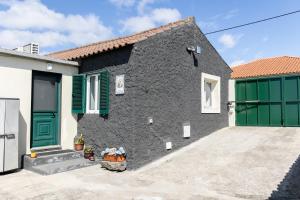 ein schwarz-grünes Haus mit grünen Türen in der Unterkunft Casa do Armando in Achadinha