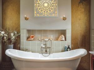 a bath tub in a bathroom with a tile wall at The Challoners in Robertsbridge