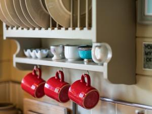 two red coffee mugs hanging from a wall in a kitchen at The Challoners in Robertsbridge