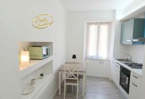 a white kitchen with a table and a microwave at Suite Arcobaleno in Deiva Marina