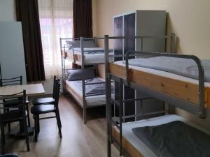 a room with four bunk beds and a table and a chair at Sitya Hostel München in Munich