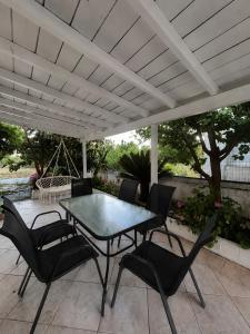 a patio table and chairs under a white pergola at Stone & Sea Retreat in Órmos Marathokámpou