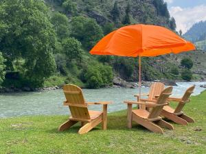 two chairs and an umbrella next to a river at Woodland Resort in Naran