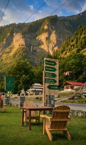 a picnic table and a bench in front of a mountain at Woodland Resort in Naran