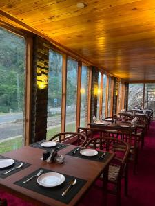 a dining room with tables and chairs and windows at Woodland Resort in Naran