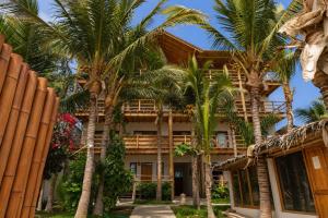 a hotel with palm trees in front of it at Los Cocos de Vichayito in Vichayito