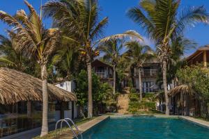 a pool in front of a resort with palm trees at Los Cocos de Vichayito in Vichayito